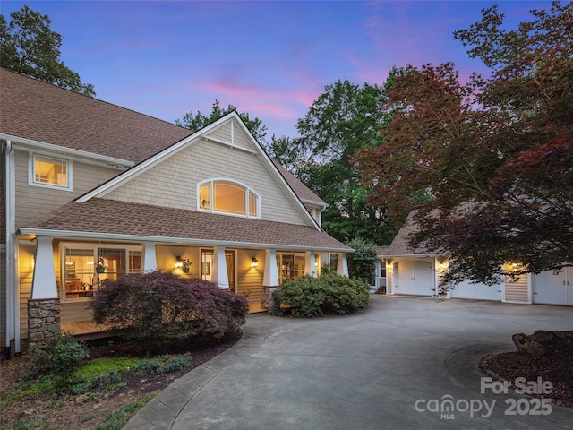 303 S Braeside Ct, Asheville, NC 28803 - craftsman-style home featuring a shingled roof, a porch, curved driveway, and stone siding