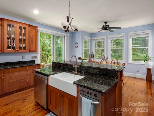 303 S Braeside Ct, Asheville, NC 28803 - kitchen featuring stainless steel dishwasher, brown cabinets, hanging light fixtures, light wood-style flooring, and glass insert cabinets
