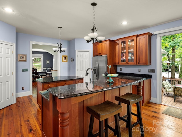 303 S Braeside Ct, Asheville, NC 28803 - kitchen with stainless steel refrigerator with ice dispenser, an island with sink, arched walkways, brown cabinets, and hardwood / wood-style floors