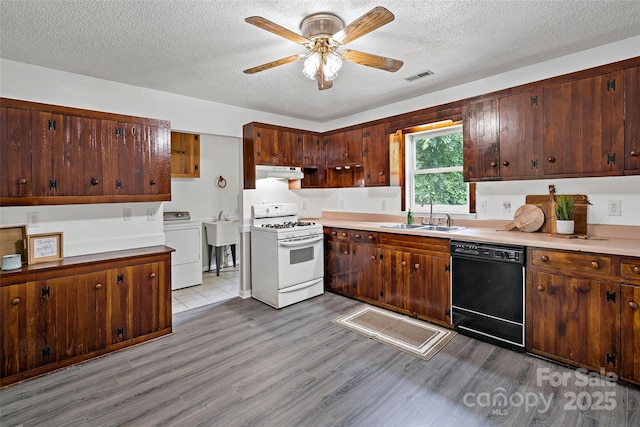 2526 Hankins Rd, Marion, NC 28752 - kitchen featuring white range with gas cooktop, black dishwasher, washer / clothes dryer, under cabinet range hood, and light wood finished floors