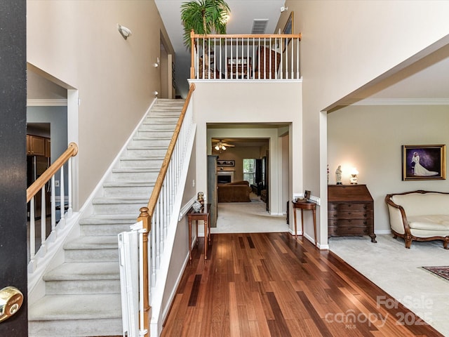 3533 Weddington Ridge Ln, Matthews, NC 28105 - staircase featuring crown molding, wood finished floors, a towering ceiling, ceiling fan, and a fireplace