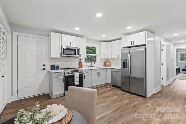 10514 Harbor Dr, Charlotte, NC 28214 - kitchen with appliances with stainless steel finishes, light countertops, decorative backsplash, wood finished floors, and recessed lighting