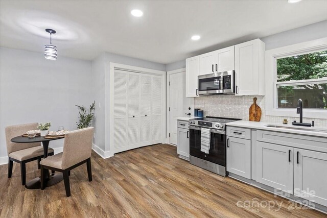 10514 Harbor Dr, Charlotte, NC 28214 - kitchen featuring appliances with stainless steel finishes, tasteful backsplash, wood finished floors, light countertops, and recessed lighting