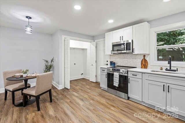 10514 Harbor Dr, Charlotte, NC 28214 - kitchen with appliances with stainless steel finishes, backsplash, light countertops, light wood-style flooring, and recessed lighting