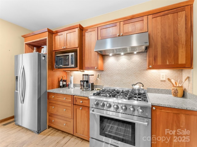 253 Sandy Ln, Brevard, NC 28712 - kitchen with under cabinet range hood, stainless steel appliances, brown cabinets, and light wood-style floors