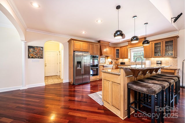 4010 Carlton Dr, Claremont, NC 28610 - kitchen with appliances with stainless steel finishes, arched walkways, brown cabinetry, light stone counters, and crown molding