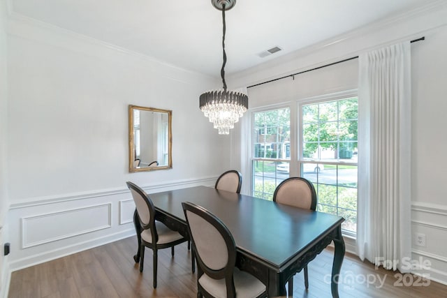 10418 Pullengreen Dr, Charlotte, NC 28277 - dining room featuring a decorative wall, wood finished floors, crown molding, a chandelier, and wainscoting