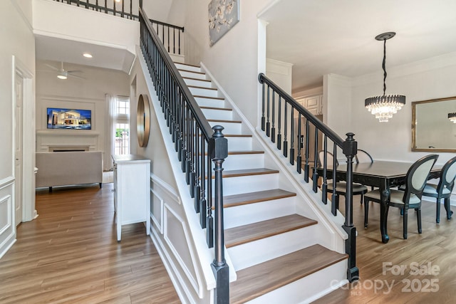 10418 Pullengreen Dr, Charlotte, NC 28277 - stairway featuring ceiling fan, wood finished floors, a chandelier, and a fireplace