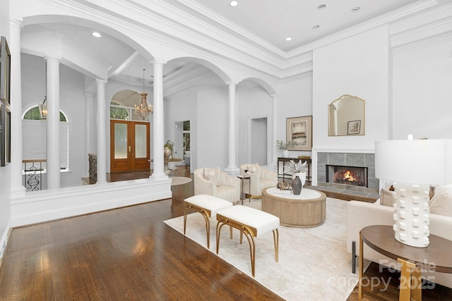7912 Baltusrol Ln, Charlotte, NC 28210 - living room with wood finished floors, a high ceiling, a tile fireplace, decorative columns, and crown molding
