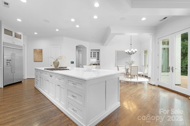 7912 Baltusrol Ln, Charlotte, NC 28210 - kitchen featuring stainless steel appliances, arched walkways, white cabinetry, a center island, and wood finished floors
