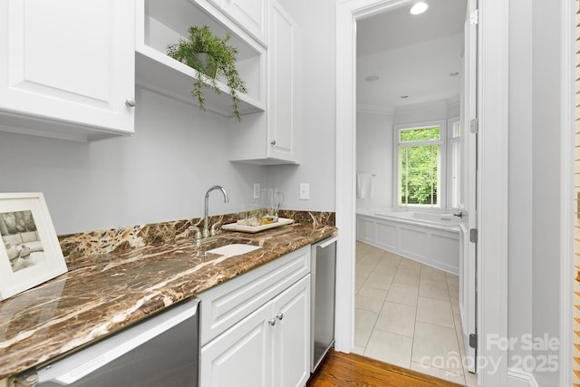 7912 Baltusrol Ln, Charlotte, NC 28210 - kitchen featuring stainless steel dishwasher, white cabinetry, dark stone counters, ornamental molding, and light tile patterned flooring