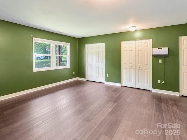 14 Spring Lake Dr, Fletcher, NC 28732 - unfurnished bedroom with multiple closets, dark wood-style flooring, and a wall unit AC