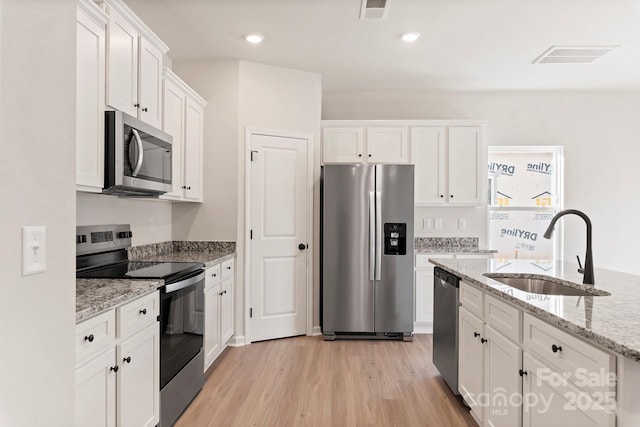 3315 Burberry Dr, Gastonia, NC 28052 - kitchen with appliances with stainless steel finishes, white cabinets, light wood-type flooring, light stone countertops, and recessed lighting