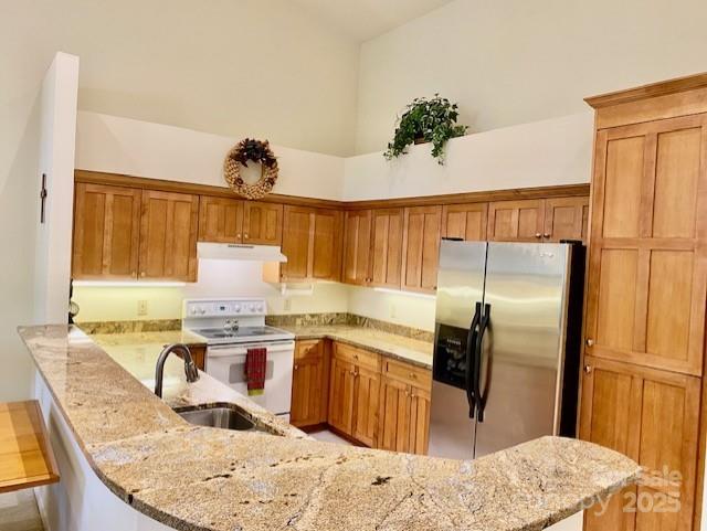 186 Stonecrest Ct, Lake Lure, NC 28746 - kitchen featuring stainless steel fridge, electric range, exhaust hood, a peninsula, and light stone countertops