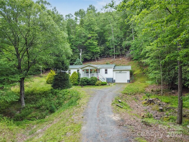 275 Bulldog Ln, Green Mountain, NC 28740 - view of front of property with driveway, a metal roof, a wooded view, and a garage