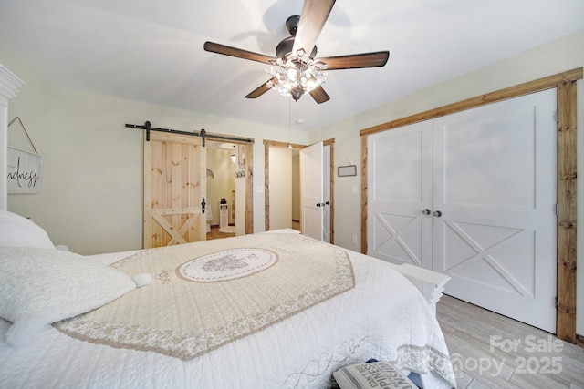4592 Reid Rd, Edgemoor, SC 29712 - bedroom featuring a barn door, light wood finished floors, ceiling fan, and a closet