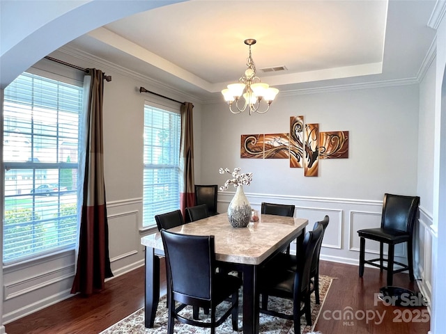 11511 Wilson Mill Ln, Pineville, NC 28134 - dining space with a chandelier, a raised ceiling, a decorative wall, dark wood-type flooring, and arched walkways
