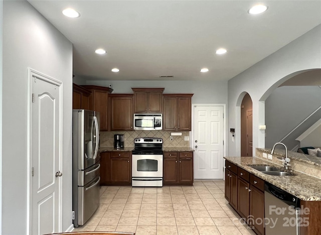 11511 Wilson Mill Ln, Pineville, NC 28134 - kitchen featuring stainless steel appliances, arched walkways, tasteful backsplash, light tile patterned floors, and recessed lighting
