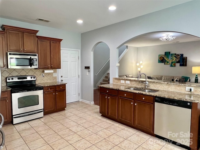 11511 Wilson Mill Ln, Pineville, NC 28134 - kitchen featuring stainless steel appliances, arched walkways, decorative backsplash, open floor plan, and light tile patterned floors