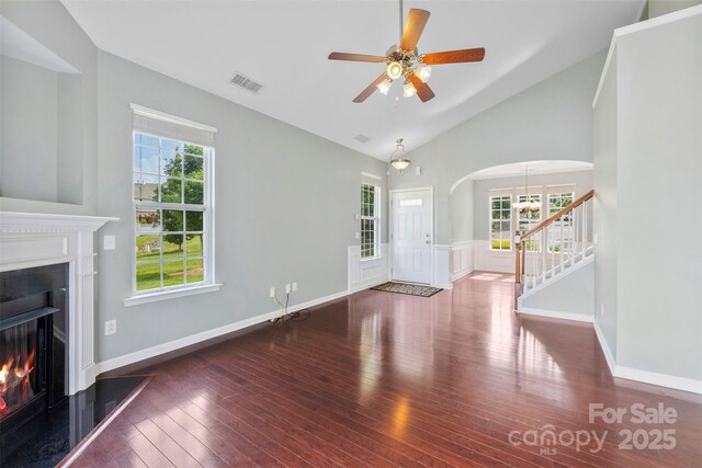 448 River Park Rd, Belmont, NC 28012 - unfurnished living room with arched walkways, hardwood / wood-style flooring, a warm lit fireplace, vaulted ceiling, and a ceiling fan