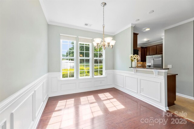 448 River Park Rd, Belmont, NC 28012 - unfurnished dining area with a chandelier, crown molding, wainscoting, wood finished floors, and a decorative wall