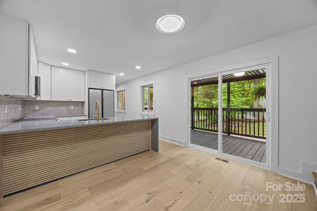 6501 Piney Path Rd, Charlotte, NC 28212 - kitchen featuring light wood finished floors, backsplash, white cabinets, a peninsula, and appliances with stainless steel finishes