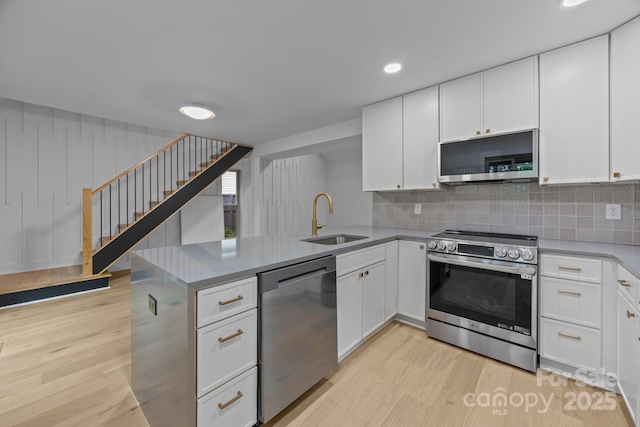 6501 Piney Path Rd, Charlotte, NC 28212 - kitchen with appliances with stainless steel finishes, light wood finished floors, a peninsula, white cabinetry, and recessed lighting