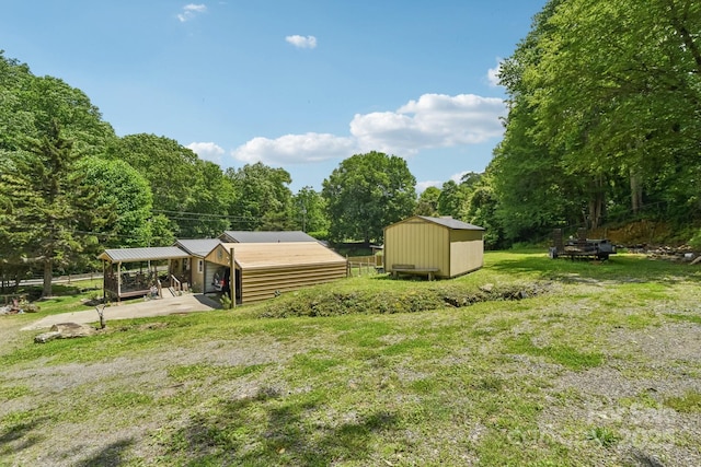 19 Lockman Rd, Maggie Valley, NC 28751 - view of green lawn with concrete driveway, a storage shed, a forest view, and an attached carport