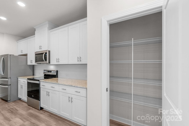 1022 Jeffery Dean Ct, Albemarle, NC 28001 - kitchen with appliances with stainless steel finishes, light wood-style floors, white cabinets, recessed lighting, and light stone countertops