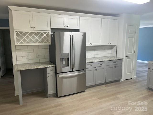 11021 Scrimshaw Ln, Charlotte, NC 28215 - kitchen with stainless steel refrigerator with ice dispenser, light wood finished floors, decorative backsplash, and light stone countertops