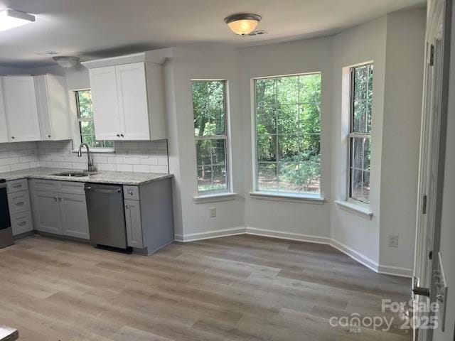 11021 Scrimshaw Ln, Charlotte, NC 28215 - kitchen with stainless steel dishwasher, tasteful backsplash, light wood-style flooring, gray cabinets, and white cabinetry