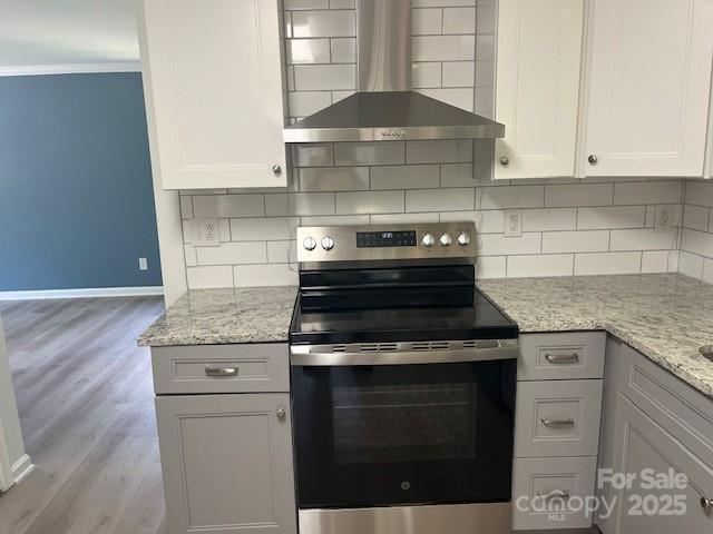 11021 Scrimshaw Ln, Charlotte, NC 28215 - kitchen with stainless steel range with electric cooktop, wall chimney range hood, ornamental molding, light wood-style flooring, and tasteful backsplash