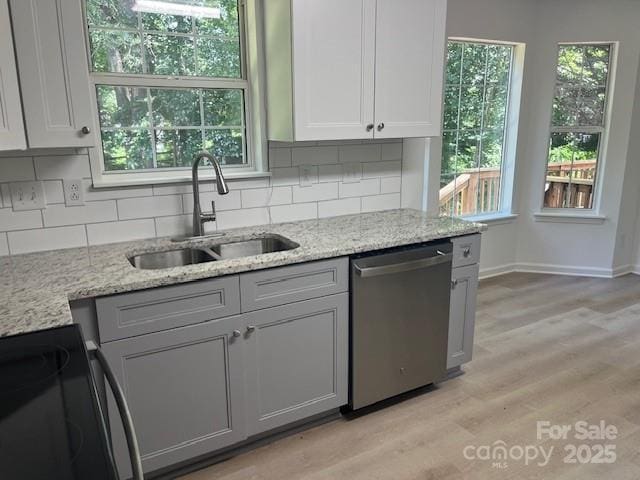 11021 Scrimshaw Ln, Charlotte, NC 28215 - kitchen featuring dishwasher, electric range, decorative backsplash, light wood-style flooring, and light stone counters