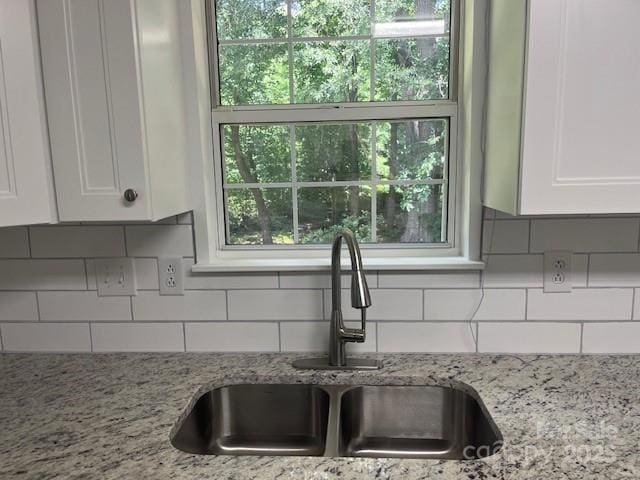 11021 Scrimshaw Ln, Charlotte, NC 28215 - kitchen featuring white cabinetry, tasteful backsplash, light stone countertops, and healthy amount of natural light