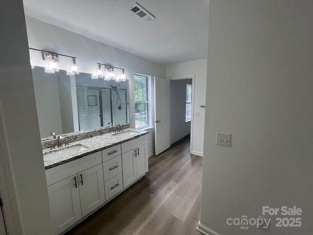 11021 Scrimshaw Ln, Charlotte, NC 28215 - bathroom featuring double vanity, wood finished floors, and a stall shower