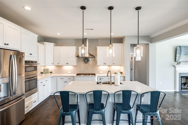 3041 Winged Teal Ct, Belmont, NC 28012 - kitchen featuring stainless steel appliances, wall chimney range hood, dark wood-style floors, decorative backsplash, and a kitchen breakfast bar