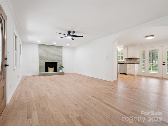 10728 Forest Dr, Matthews, NC 28105 - unfurnished living room with a ceiling fan, light wood-style floors, crown molding, a fireplace, and arched walkways