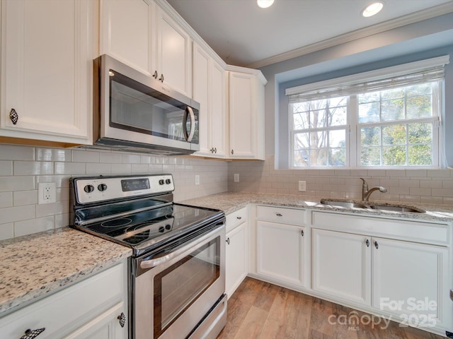 120 Prairie View Ct, Belmont, NC 28012 - kitchen featuring appliances with stainless steel finishes, light wood-style flooring, white cabinets, light stone counters, and ornamental molding