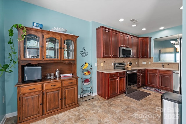 1498 Burrell Ave NW, Concord, NC 28027 - kitchen featuring appliances with stainless steel finishes, tasteful backsplash, glass insert cabinets, recessed lighting, and light countertops