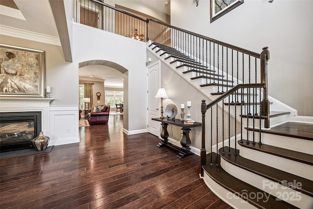 16547 Bastille Dr, Charlotte, NC 28278 - stairs featuring arched walkways, wood-type flooring, a glass covered fireplace, and ornamental molding