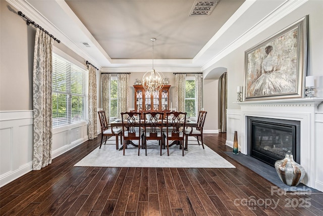 16547 Bastille Dr, Charlotte, NC 28278 - dining space with a raised ceiling, dark wood-style flooring, arched walkways, a chandelier, and a glass covered fireplace