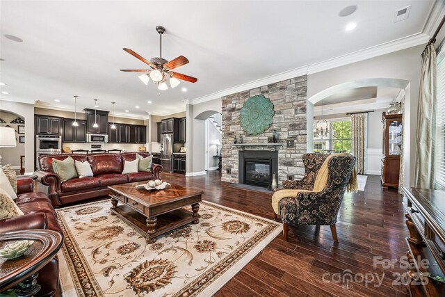 16547 Bastille Dr, Charlotte, NC 28278 - living room with arched walkways, ceiling fan, dark wood-type flooring, ornamental molding, and a fireplace