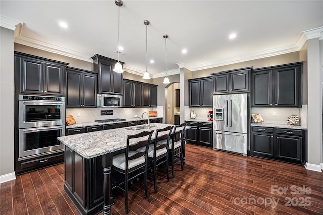 16547 Bastille Dr, Charlotte, NC 28278 - kitchen featuring appliances with stainless steel finishes, arched walkways, dark cabinetry, a center island with sink, and crown molding