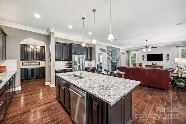 16547 Bastille Dr, Charlotte, NC 28278 - kitchen featuring arched walkways, a fireplace, appliances with stainless steel finishes, a ceiling fan, and dark wood-type flooring