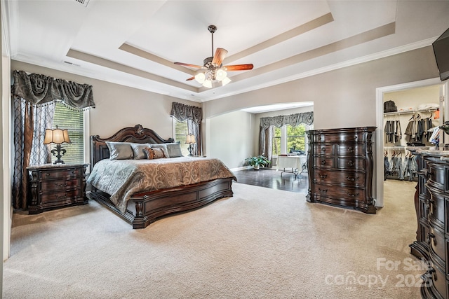 16547 Bastille Dr, Charlotte, NC 28278 - carpeted bedroom featuring a raised ceiling, a walk in closet, ornamental molding, a ceiling fan, and arched walkways