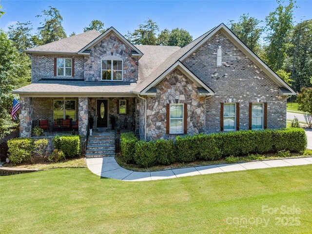 16547 Bastille Dr, Charlotte, NC 28278 - craftsman house featuring stone siding, a front lawn, covered porch, a shingled roof, and brick siding