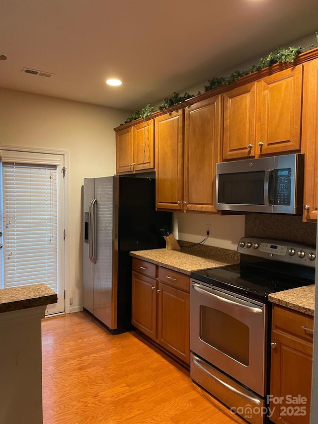 13116 Erwin Rd, Charlotte, NC 28273 - kitchen featuring stainless steel appliances, light wood-style floors, recessed lighting, light stone countertops, and brown cabinetry