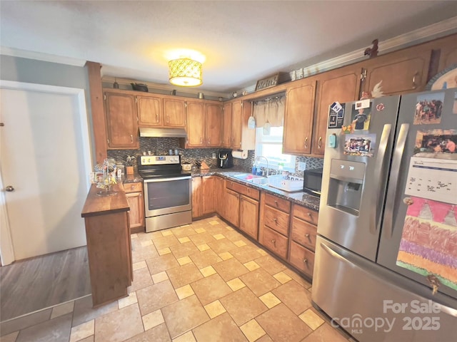 803 Bannon Pl, Lenoir, NC 28645 - kitchen featuring appliances with stainless steel finishes, under cabinet range hood, dark countertops, brown cabinets, and backsplash