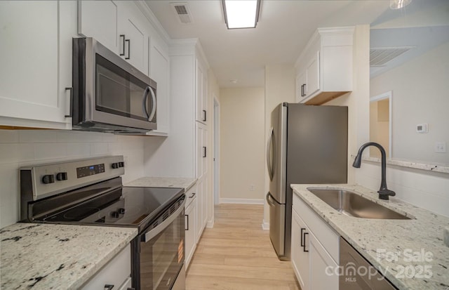 903 Brookdale St, Kannapolis, NC 28083 - kitchen featuring appliances with stainless steel finishes, light wood-type flooring, white cabinets, and tasteful backsplash