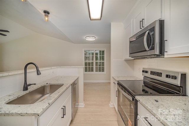 903 Brookdale St, Kannapolis, NC 28083 - kitchen featuring appliances with stainless steel finishes, light wood-style floors, white cabinets, lofted ceiling, and tasteful backsplash